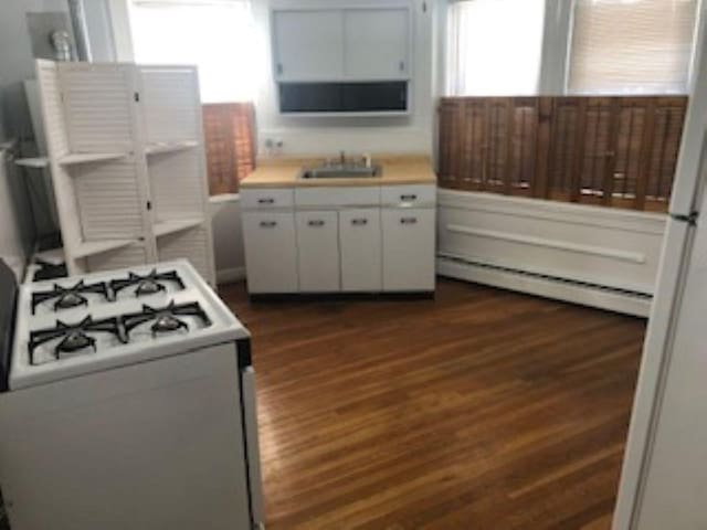 kitchen featuring dark wood-style floors, a sink, a baseboard heating unit, and white gas range oven