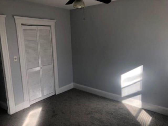 unfurnished bedroom featuring ceiling fan, baseboards, and dark colored carpet