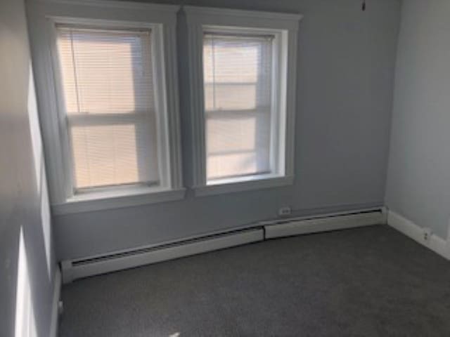 carpeted empty room featuring baseboard heating