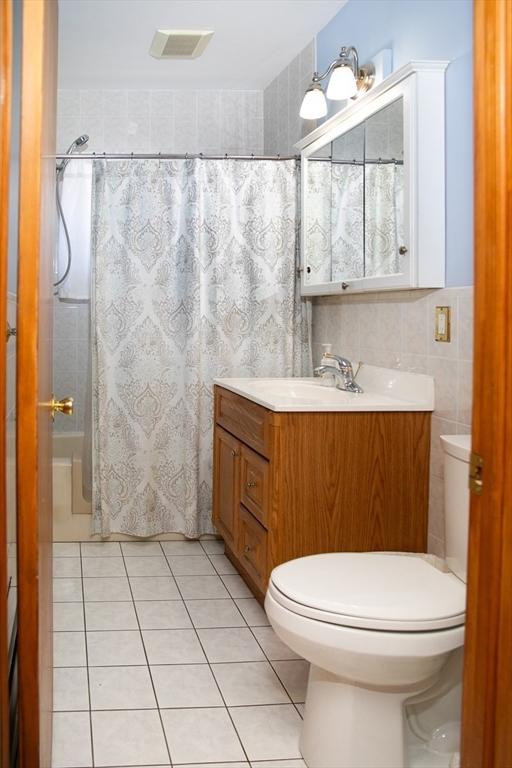 bathroom featuring tile patterned floors, toilet, tile walls, vanity, and a shower with shower curtain