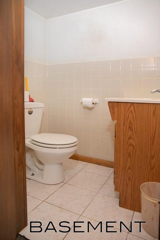 bathroom with tile patterned flooring, vanity, tile walls, and toilet