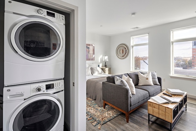 washroom with hardwood / wood-style flooring and stacked washer and clothes dryer