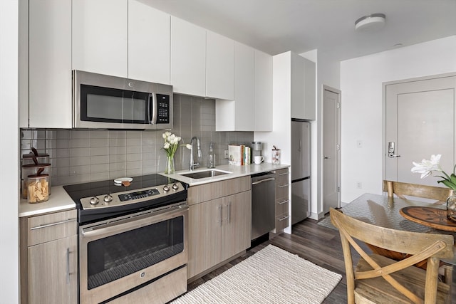 kitchen featuring sink, stainless steel appliances, dark hardwood / wood-style flooring, decorative backsplash, and white cabinets