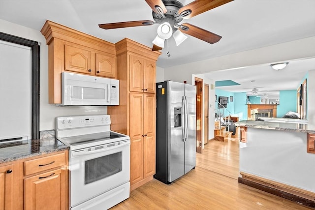 kitchen with white appliances, ceiling fan, dark stone countertops, light wood-type flooring, and light brown cabinetry