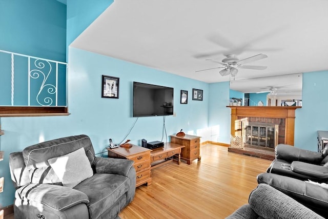 living room with ceiling fan, wood-type flooring, and a fireplace