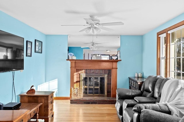 living room with ceiling fan, light hardwood / wood-style floors, and a fireplace