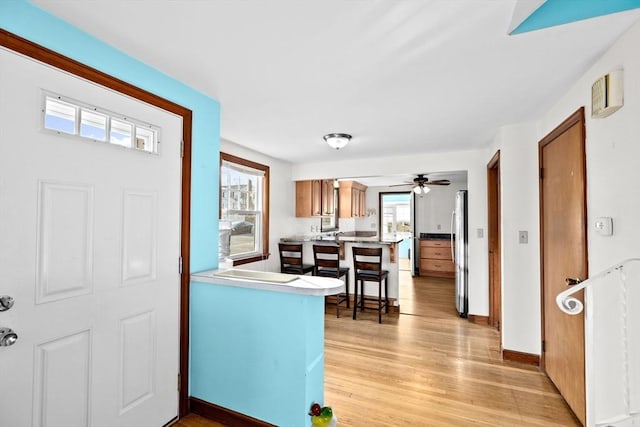 entryway with ceiling fan, a wealth of natural light, and light hardwood / wood-style flooring