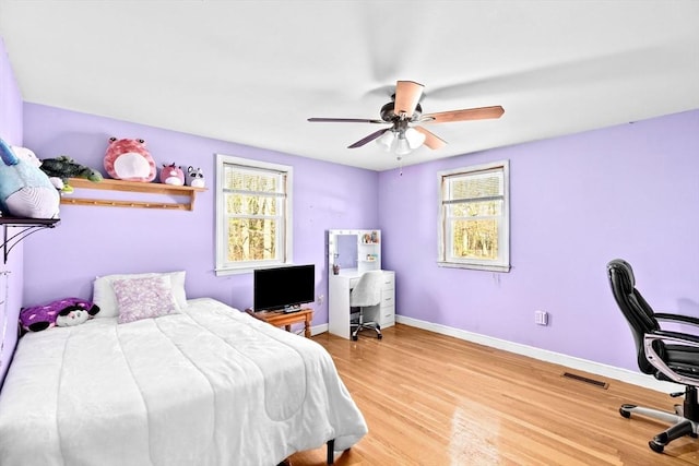 bedroom with hardwood / wood-style floors, multiple windows, and ceiling fan