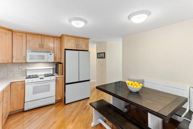 kitchen featuring decorative backsplash, light wood-type flooring, light countertops, light brown cabinets, and white appliances