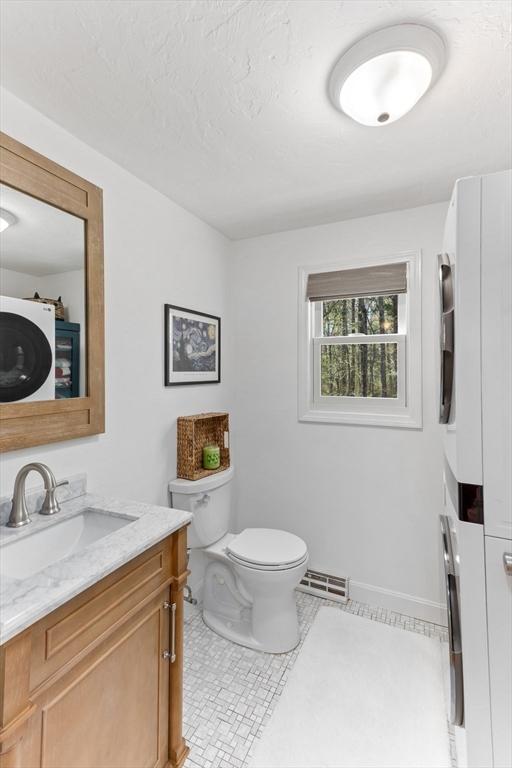 bathroom featuring vanity, baseboards, toilet, and visible vents