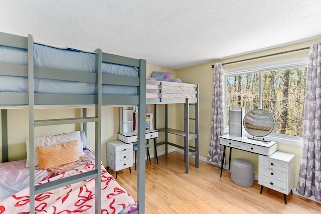 bedroom featuring a textured ceiling, baseboards, and wood finished floors