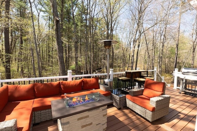 deck with an outdoor living space with a fire pit and a forest view