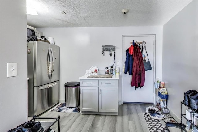 kitchen with light hardwood / wood-style floors, stainless steel fridge, and a textured ceiling