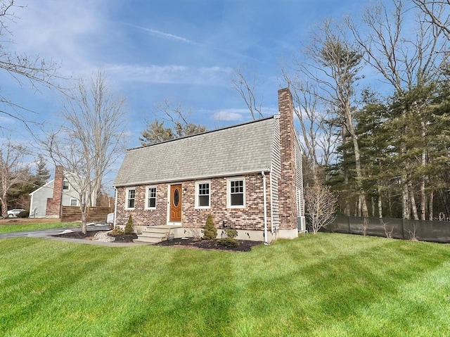 view of front of house with brick siding, a chimney, a front lawn, and fence