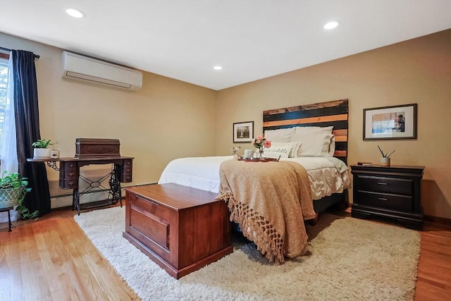 bedroom with recessed lighting, baseboards, wood finished floors, and a wall unit AC