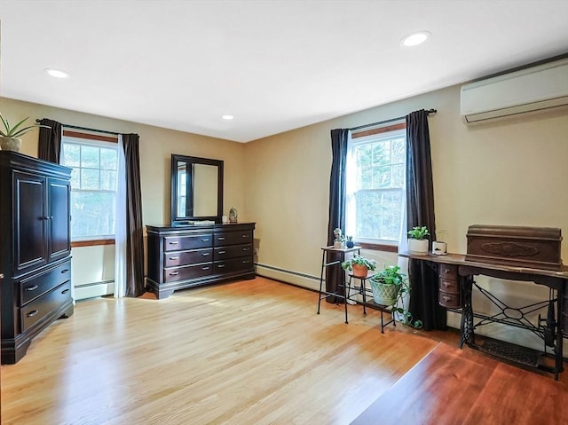 interior space featuring multiple windows, light wood finished floors, baseboard heating, and a wall mounted AC