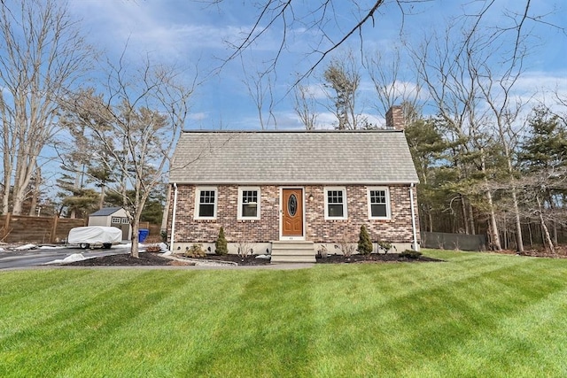 view of front of house with a front lawn, brick siding, roof with shingles, and a chimney