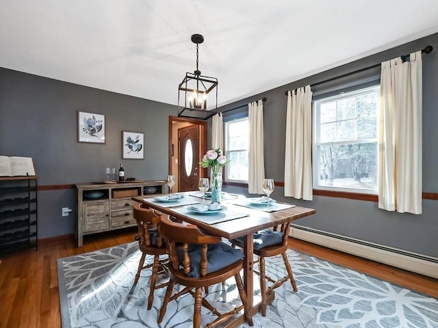 dining area with a chandelier, baseboard heating, and wood finished floors