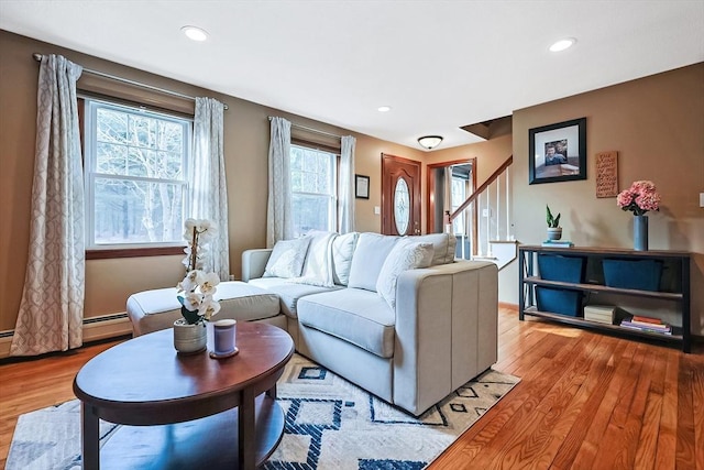 living room featuring recessed lighting, a baseboard heating unit, stairway, and light wood finished floors