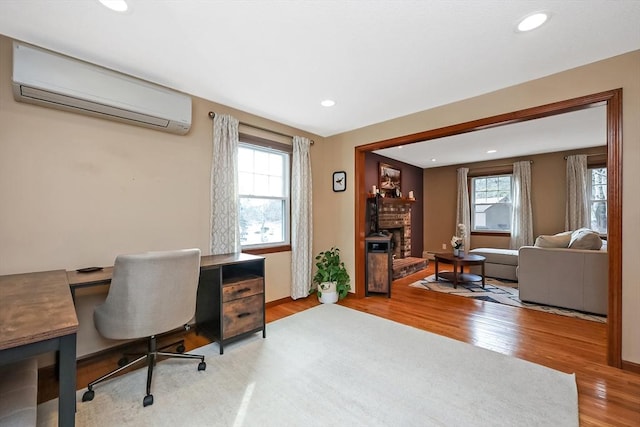 office area featuring recessed lighting, a fireplace, a wall unit AC, and wood finished floors