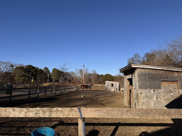 view of yard with a rural view, fence, and an outdoor structure