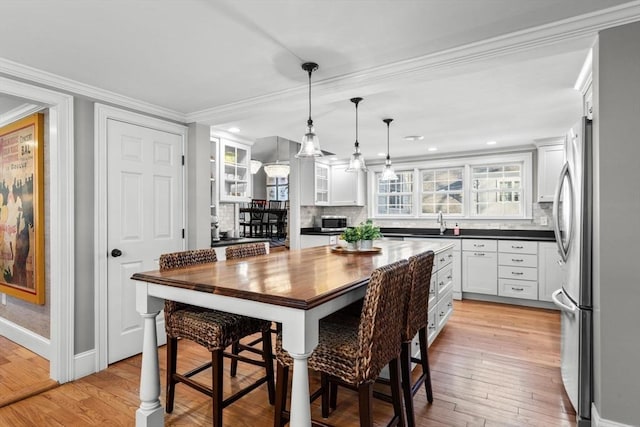 dining area featuring crown molding, sink, and light hardwood / wood-style floors