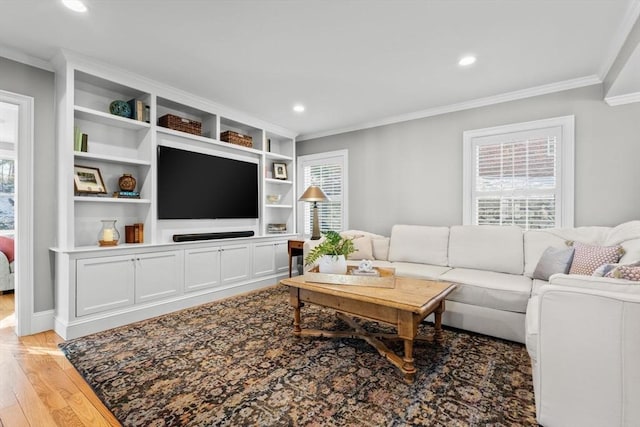 living room with crown molding, plenty of natural light, and light hardwood / wood-style flooring