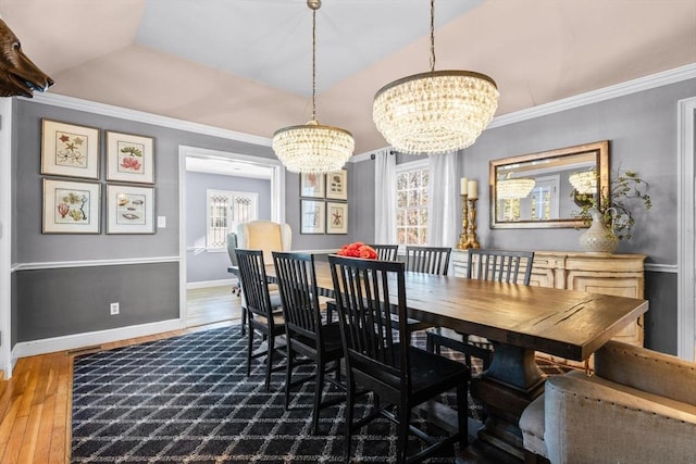 dining space featuring lofted ceiling, crown molding, wood-type flooring, and a chandelier