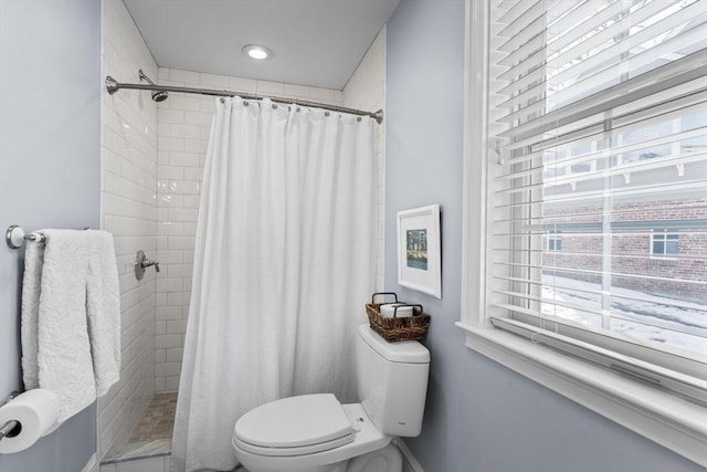 bathroom featuring toilet, curtained shower, and a wealth of natural light