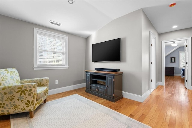 living area with vaulted ceiling and light wood-type flooring