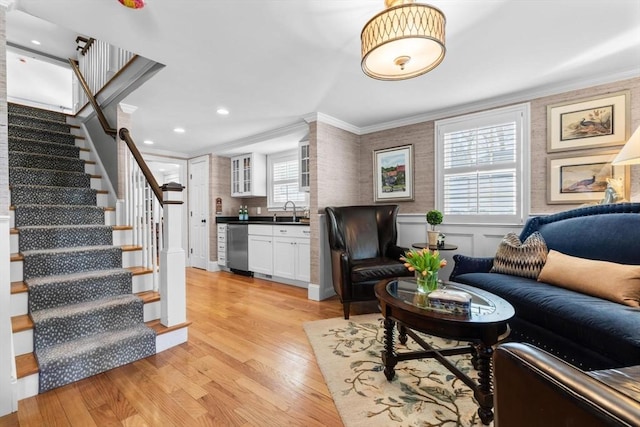 living room with crown molding, sink, and light hardwood / wood-style floors