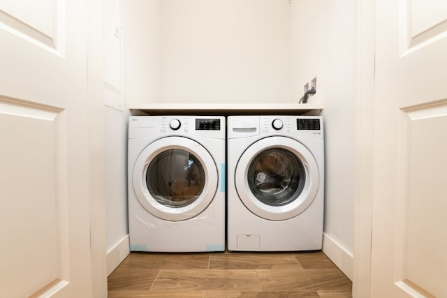 clothes washing area featuring separate washer and dryer and light hardwood / wood-style flooring