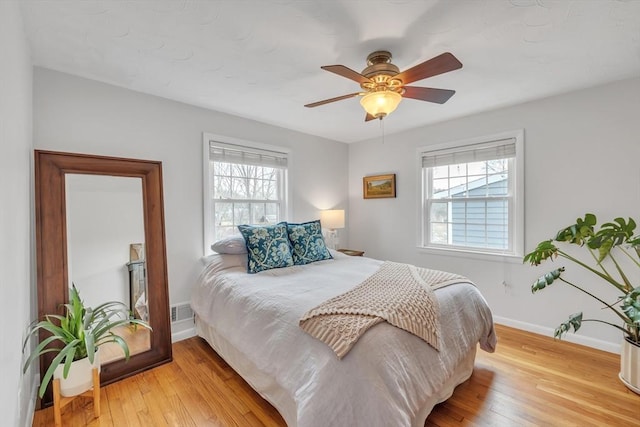 bedroom with light wood-type flooring, multiple windows, and baseboards