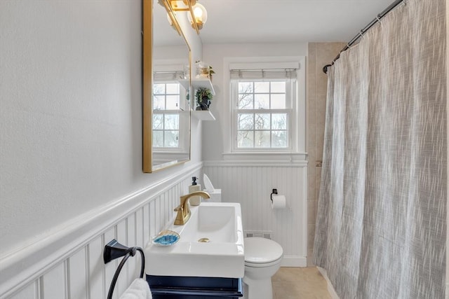 bathroom featuring vanity, a shower with curtain, tile patterned flooring, wainscoting, and toilet