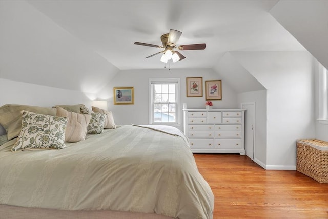 bedroom featuring light wood-type flooring, lofted ceiling, baseboards, and ceiling fan