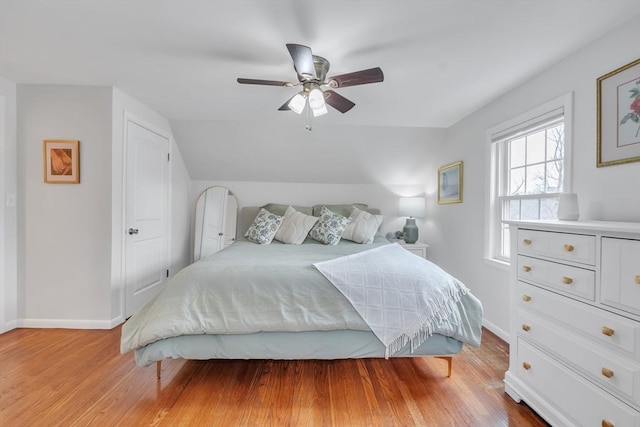 bedroom featuring baseboards, light wood-style floors, a ceiling fan, and vaulted ceiling