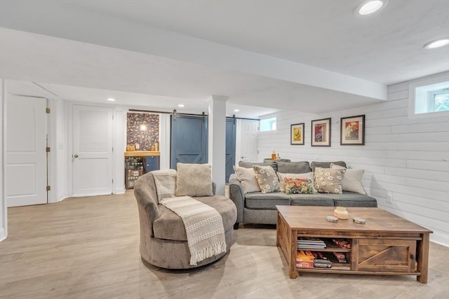 living area with recessed lighting, wood walls, light wood-style floors, and a barn door