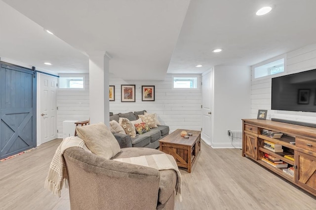 living room featuring recessed lighting, a barn door, light wood-style floors, and wooden walls