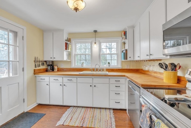 kitchen with open shelves, white cabinetry, appliances with stainless steel finishes, and a sink