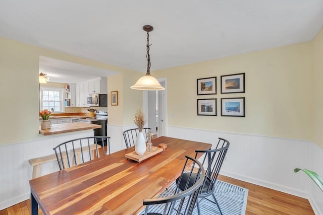 dining area featuring light wood-style flooring and wainscoting