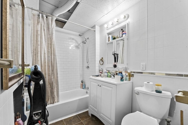 bathroom with vanity, toilet, shower / tub combo, and tile walls