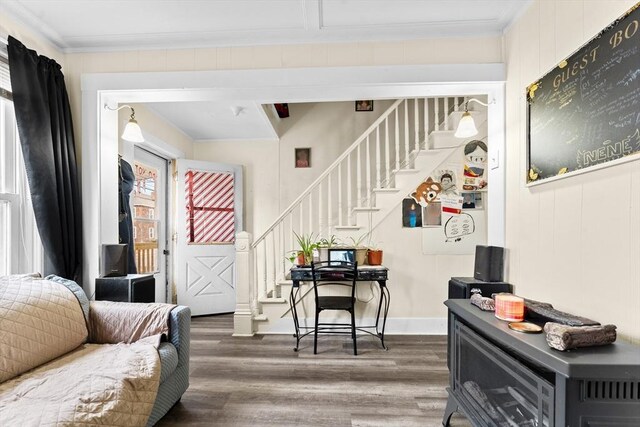 living area with crown molding, wood finished floors, and stairway