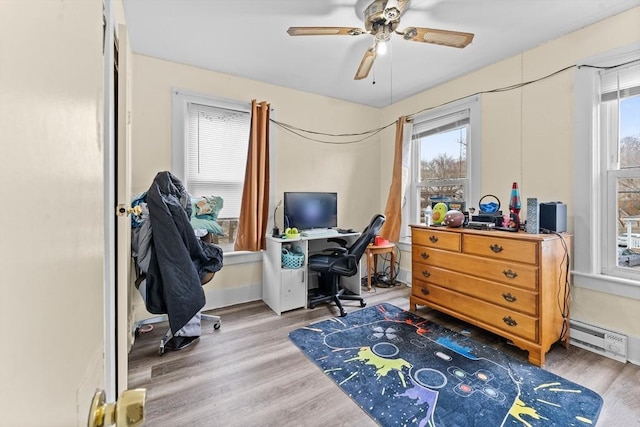 office space with a ceiling fan, a baseboard heating unit, and light wood-type flooring