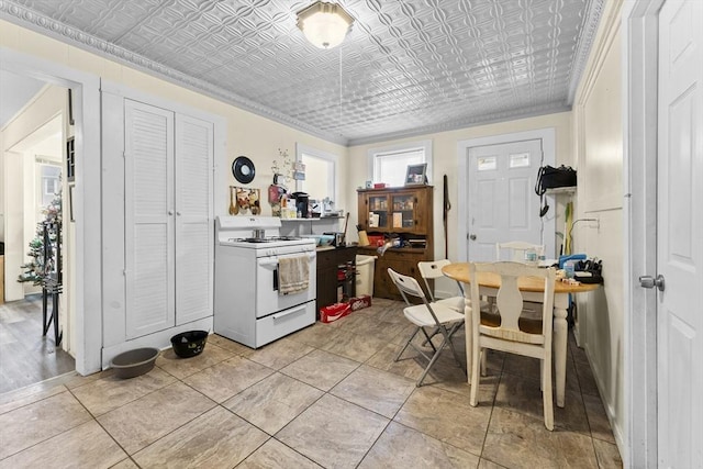 kitchen featuring an ornate ceiling, white gas range oven, ornamental molding, and light tile patterned floors