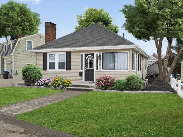 bungalow-style home with roof with shingles, a chimney, and a front lawn