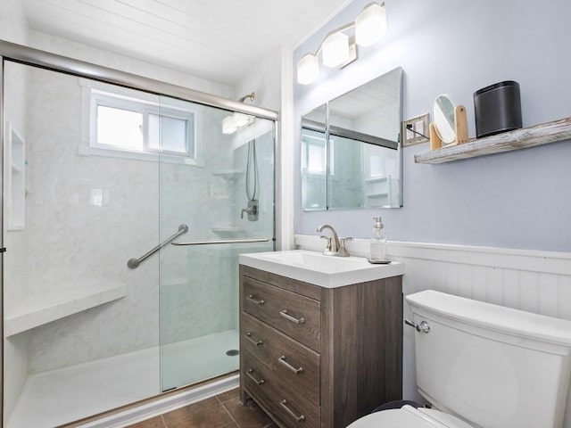 full bathroom featuring a stall shower, toilet, a wainscoted wall, tile patterned flooring, and vanity