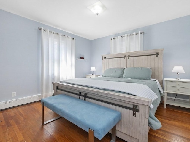 bedroom featuring a baseboard heating unit, baseboards, and wood finished floors