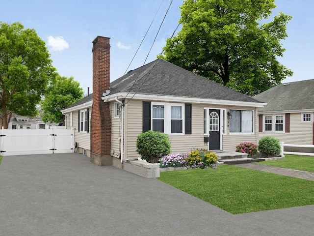 view of front of property with aphalt driveway, fence, a gate, a chimney, and a front yard