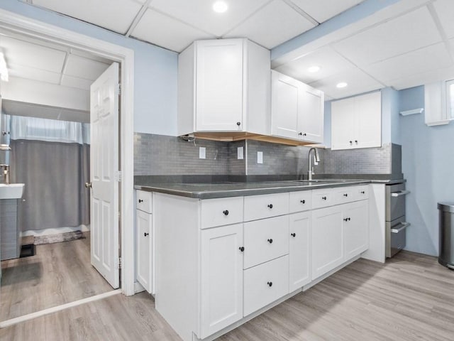 kitchen featuring dark countertops, light wood-type flooring, a sink, and white cabinets