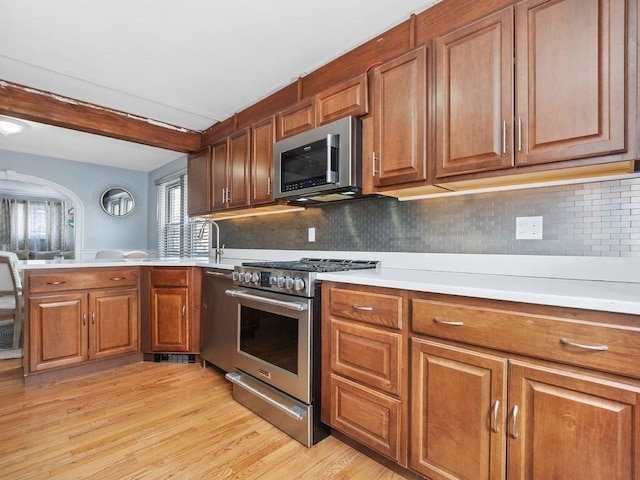 kitchen with light countertops, appliances with stainless steel finishes, light wood-type flooring, and brown cabinets